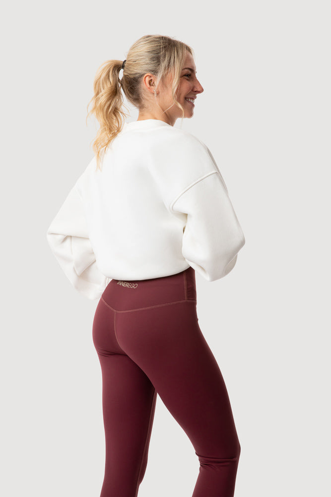 women wearing white oversized INNER EGO embossed sweatshirt and rouge red flex-set leggings - white background